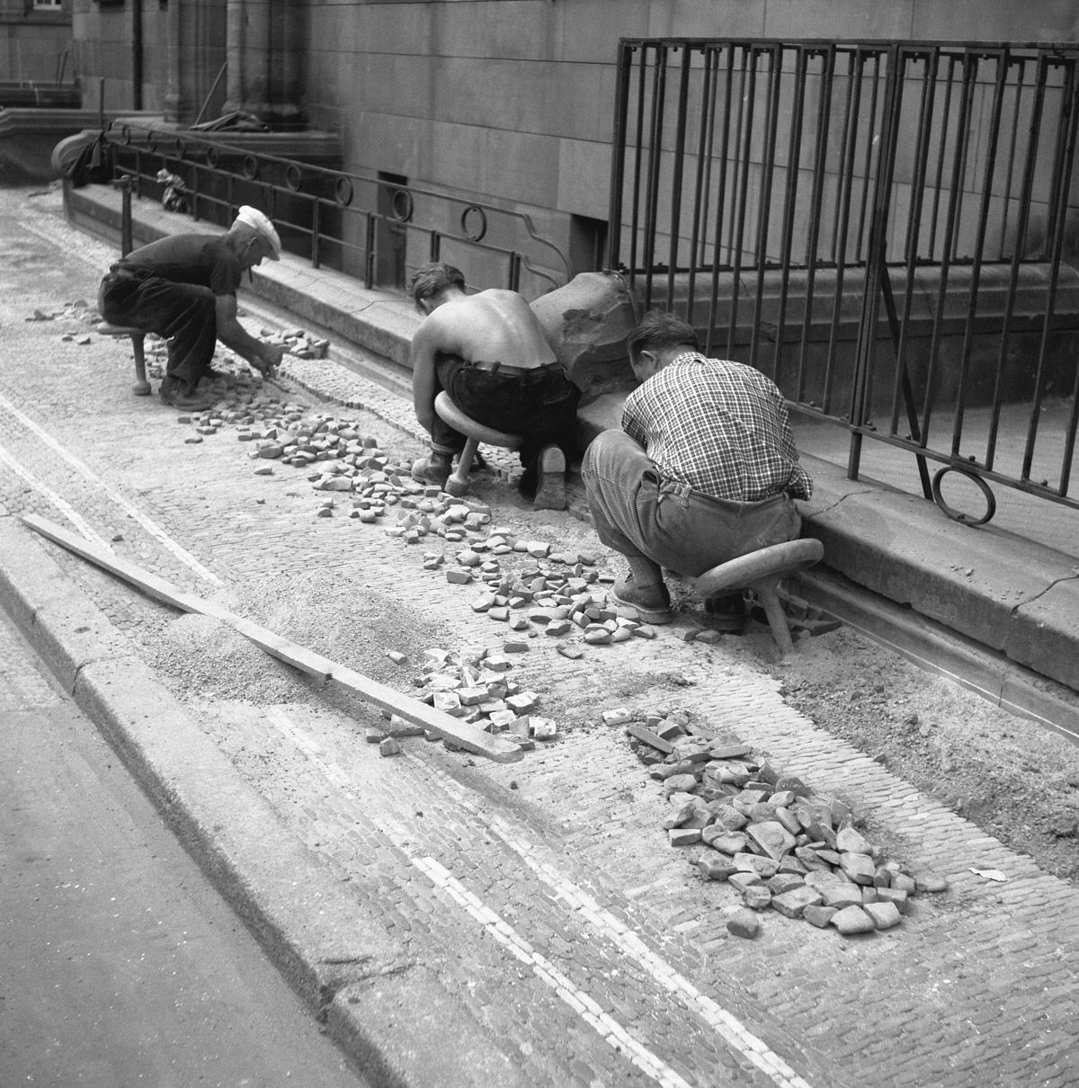 Straßenarbeiter\*innen pflastern eine Straße mit Natursteinen, Freiburg ca. 1945 bis 1955